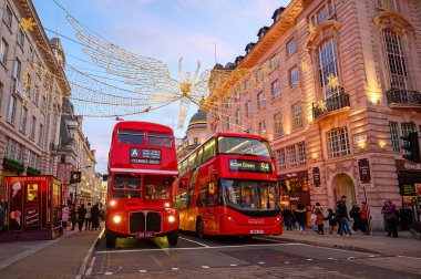 Londra Piccadilly Sirki 'nde iki kırmızı Londra otobüsü. Bu Piccadilly Circus 'un güneyinden Regent Street Saint James' e doğru olan manzara. Gün batımından hemen sonra akşam manzarası