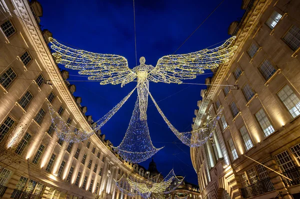 Londra, İngiltere 'de Regent Caddesi boyunca mimarlık. Regent Caddesi 'nin akşam manzarası. Yolun üstünde Noel ışıkları var..