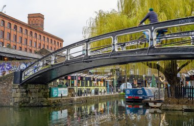 Camden Town, Londra, İngiltere: Camden Market yakınlarındaki Regents Kanalını yaya köprüsünde söğüt ağacıyla geçen bir bisikletçi.