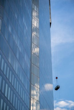 Londra, İngiltere: 22 Bishopsgate ya da Yirmi İki 'nin gökyüzü ve bulutları yansıtan detaylı görüntüsü. 8 Bishopsgate 'in tepesine bir konteynır taşınıyor..