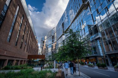 Battersea, Londra, İngiltere: Battersea Elektrik Santrali 'nin (solda) yanındaki Circus Road West boyunca yürüyen insanlar şimdi alışveriş ve tatil beldesi olarak yeniden geliştirildi.