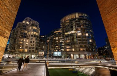 Battersea, Londra, İngiltere: Battersea yakınlarındaki yeni apartman binaları ve otel. Elektrik santralinin güney girişinin duvarları tarafından çerçevelenmiş gece görüşü.