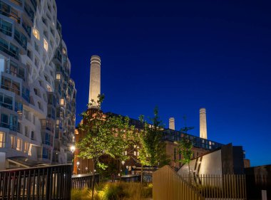 Battersea, Londra, İngiltere: Battersea Elektrik İstasyonu 'nun gece görüşü şimdi bir alışveriş ve eğlence merkezi olarak yeniden geliştirildi. Prospect Yolu 'ndan ön planda ağaçlarla metro istasyonunun yakınında görüldü..