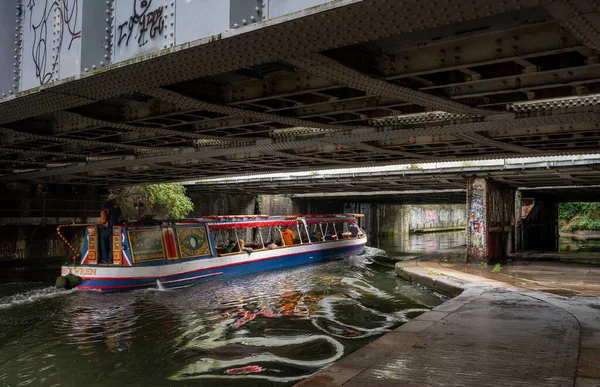 Londra, İngiltere: Londra 'da Regent' s Canal 'da hareket bulanıklığı olan bir turist teknesi. Gemi St. John Ormanı yakınlarındaki bir yol köprüsünün altından geçiyor..