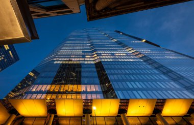 Londra, İngiltere: 22 Bishopsgate veya TwentyTwo in the City of London ofis ışıklarıyla. Direk aşağıdan yukarı bakıyor ve diğer binalar tarafından çerçeveleniyor..