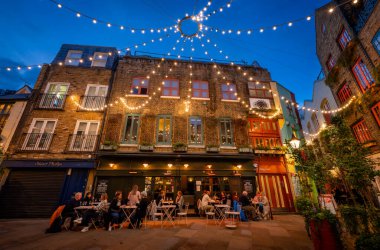 Londra, İngiltere: Londra 'nın merkezindeki Covent Garden bölgesinde Neal' s Yard. İnsanlar akşam bir restoranın önünde oturuyorlar..