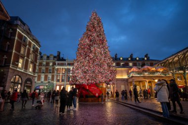 Londra, İngiltere - 8 Kasım 2023: Covent Garden Market 'in dışındaki büyük süslü Noel ağacı. İnsanlar ağaçtaki ışıklara hayran. Peyzaj yönelimi.