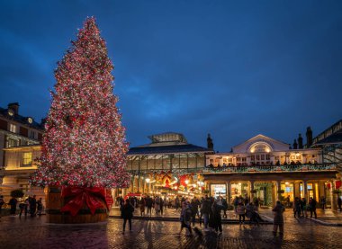 Londra, İngiltere - 8 Kasım 2023: Arkasında Covent Garden Market bulunan büyük süslü Noel ağacı. İnsanlar marketin önünden geçerken sokakta yürürler..