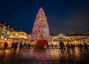 Londra, İngiltere - 8 Kasım 2023: Arkasında Covent Garden Market bulunan büyük süslü Noel ağacı. İnsanlar ağaçtaki ışıklara hayran. Peyzaj yönelimi.