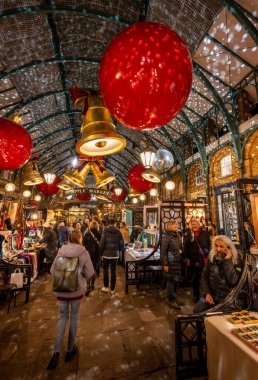 Londra, İngiltere - 8 Kasım 2023: Covent Garden Market ve Noel süslemeleri. Çanlar ve mücevherler çatıdan sarkıyor. İnsanlar Apple Market 'ten Noel alışverişi yapıyorlar..