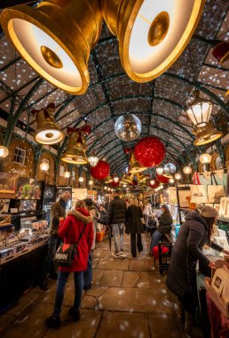 Londra, İngiltere - 8 Kasım 2023: Covent Garden Market ve Noel süslemeleri. Çanlar ve mücevherler çatıdan sarkıyor. İnsanlar Apple Market 'ten Noel alışverişi yapıyorlar..