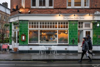 Bermondsey, Londra, İngiltere: Londra 'nın Southwark ilçesindeki Bermondsey Caddesi' ndeki Garrison Halk Evi 'nde iki kişi barın önünden geçiyor.