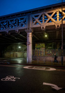Southwark, Londra, İngiltere: Londra 'nın Southwark ilçesinde Whites Grounds Paten Pisti' nin altından Greenwich Demiryolu Viaduct 'a giden Druid Caddesi boyunca yürüyen adam.