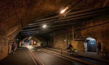 Southwark, London, UK: Bermondsey Street passing through a road tunnel under the London Bridge to Greenwich Railway Viaduct with cyclist and pedestrians. clipart