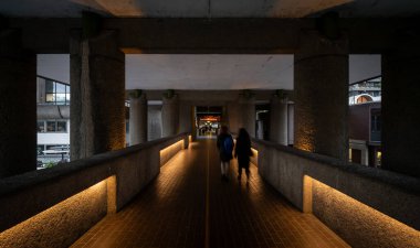 London, UK: High-level walkway on the Barbican Estate in the City of London leading to the Barbican Centre. With people walking. Brutalist architecture in London. clipart