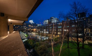 Londra, İngiltere: Londra 'daki Barbican Malikanesi' nin bahçesi ve gölü olan gece manzarası. Barbican Malikanesi, Londra 'daki Brutalist mimarinin önemli bir örneğidir..