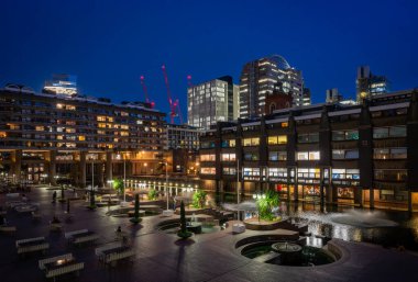 Londra, İngiltere: Londra 'daki Barbican Malikanesi' nin gölü ve çeşmeleri olan gece manzarası. Barbican Malikanesi, Londra 'daki Brutalist mimarinin önemli bir örneğidir..