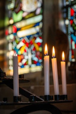 Kilisede mumlar, arkasında vitray camlar var..