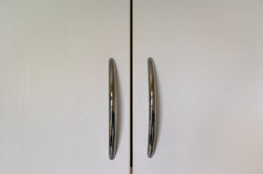 Ortasında gümüş renkli sapları olan beyaz dolap kapıları..