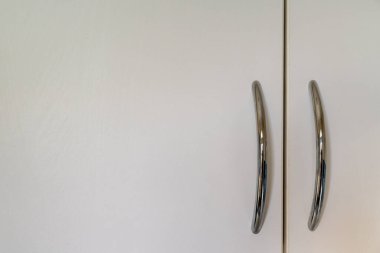 Sağda gümüş renkli saplı beyaz dolap kapakları var. Boşluğu sola kopyala.