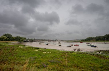 Deben nehri alçak sularda, fırtınalı bir gökyüzünün altında küçük teknelerle. İngiltere 'nin Suffolk kentindeki tarihi Woodbridge şehrine doğru bakın..
