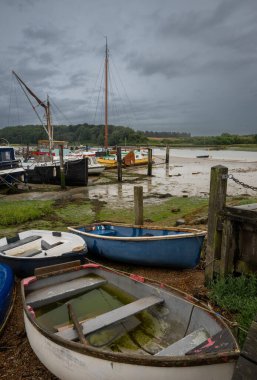 Fırtınalı bir gökyüzü altında küçük tekneler. Suffolk, İngiltere 'nin tarihi Woodbridge kasabasındaki Deben Nehri' nin akıntısı altında rıhtımın manzarası..