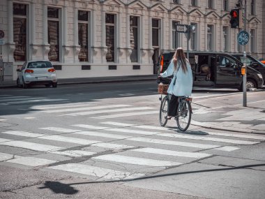 Viyana, Avusturya - Haziran 2022: Sarışın kız Viyana sokaklarında bisiklet sürüyor. Trafik ışıklarında bisikletçi