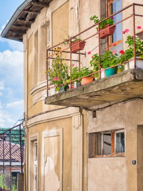 Picture with a beautiful rustic house. Front view of a balcony with flower pots in Veliko Tarnovo, Bugaria.