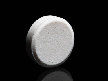 A single isolated pill or medicine tablet on black background