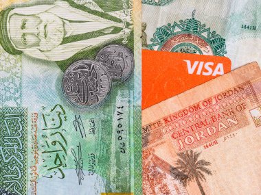 Bucharest, Romania - 02.22.2023: Macro detail picture with Jordanian dinar banknotes and a Visa credit or debit card. JOD is the official currency in The Hashemite Kingdom of Jordan