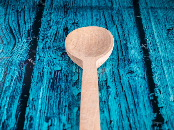 A hand made craft wooden spoon in the kitchen. Isolated spoon on blue background.
