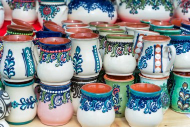 Geleneksel Romen el yapımı seramik çömlek kupaları ve sergilenen otantik kırsal dekorasyon resimleri.