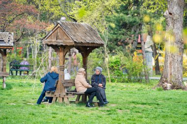 Bükreş, Romanya - Nisan 2023: Parktaki banklarda oturan ve sosyalleşen bir grup yaşlı kadın. Kral I. Mihai 'deki manzara parkı (Herestrau), Bükreş.