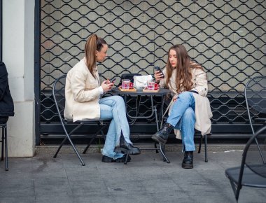 Bükreş, Romanya - Nisan 2023: Bükreş 'te iki kız arkadaş içki içiyor.