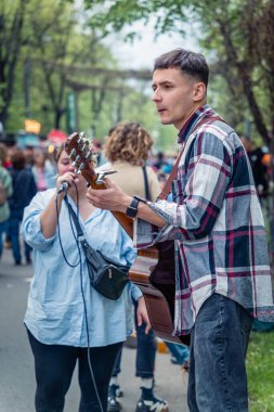 Bükreş, Romanya - Ağustos 2022: Bükreş 'in merkezinde akustik gitar çalan genç sokak sanatçısı (Zafer Caddesi - Calea Victoriei)).
