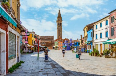 Venedik, İtalya - 30 Mayıs 2023: Venedik 'teki Burano adasında Saint Martin Piskoposu Kilisesi' nin yakınındaki çan kulesi olan su kanalı boyunca renkli evler.