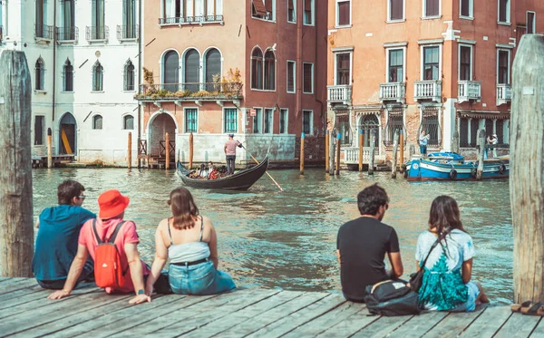 Venedik, İtalya - 30 Mayıs 2023: Tahta bir tekne iskelesinde oturan turistler Venedik 'teki Büyük Kanal' ın cennet manzarasının tadını çıkarıyorlar.