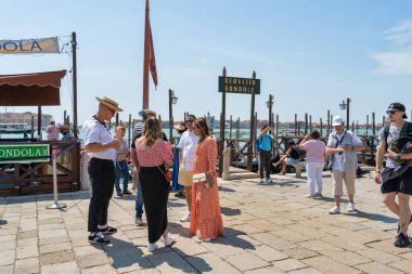 Venedik, İtalya - 31 Mayıs 2023: Gondolcu Venedik 'te gondol gezisi için bir turiste yaklaşıyor.