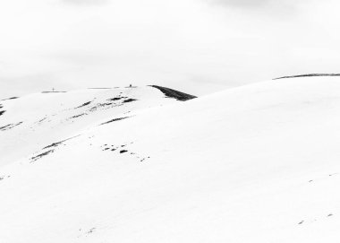 Karlı dağda yalnız bir yürüyüşçünün yürüdüğü siyah beyaz bir minimalist resim. Romanya 'daki Karpat Dağları.