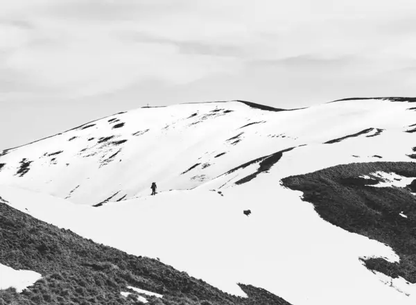 Black and white abstract minimalist picture with a lonely hiker walking on the snowy mountain. Carpathian Mountains in Romania.