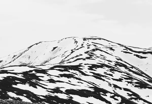 Black and white abstract minimalist picture with a mountain covered in snow.