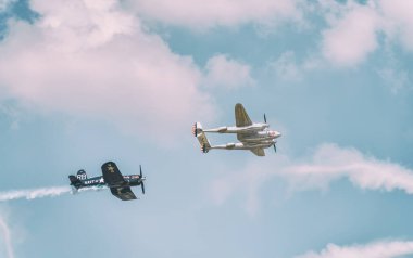 Bükreş, Romanya - Mayıs 2023: LOCKHEED P-38 Işıklandırma ve Şans F4U Corsair savaş uçakları Uçan Boğalar filosunun bir bölümü gökyüzüne doğru uçuyordu.