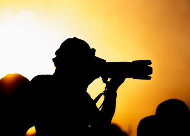 Gün batımında elinde kamera olan bir fotoğrafçının silüeti..