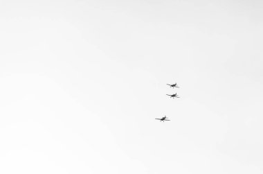 Beyaz zemin üzerinde uçan üç küçük hafif uçakla soyut asgari resim.