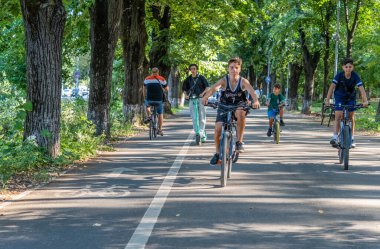 Bükreş, Romanya - 13 Ağustos 2023: Bükreş 'teki Herestrau parkında bisiklet yolunda bisiklet süren bir grup genç adam