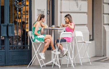 Bükreş, Romanya - 17 Haziran 2023: Bükreş 'teki eski kentte içki içen iki kız arkadaş. Bükreş 'in merkezinde Zafer Caddesi' ndeki yaya alanı (Calea Victoriei).