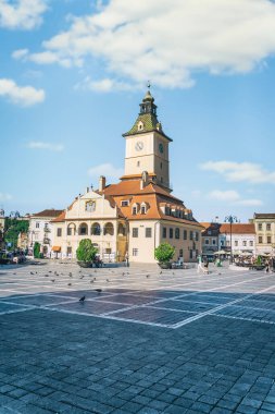 Brasov, Romanya - Eylül 02.2023: Brasov 'un eski şehir merkezindeki yaya bölgesinde turistler ve yerel halk geziniyor. Council Square 'deki belediye binası..