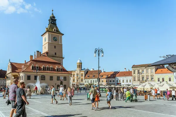 Brasov, Romanya - Eylül 02.2023: Brasov 'un eski şehir merkezindeki yaya bölgesinde turistler ve yerel halk geziniyor. Council Square 'deki belediye binası..