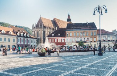 Brasov, Romanya - Eylül 02.2023: Brasov 'un eski şehir merkezindeki yaya bölgesinde turistler ve yerel halk geziniyor. Council Square 'deki belediye binası..