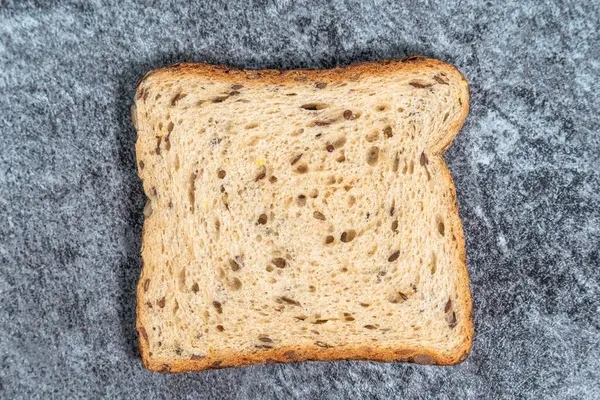 Koyu arkaplanda tohum olan bir dilim taze ekmek. Fransız tostu ile üst manzara.